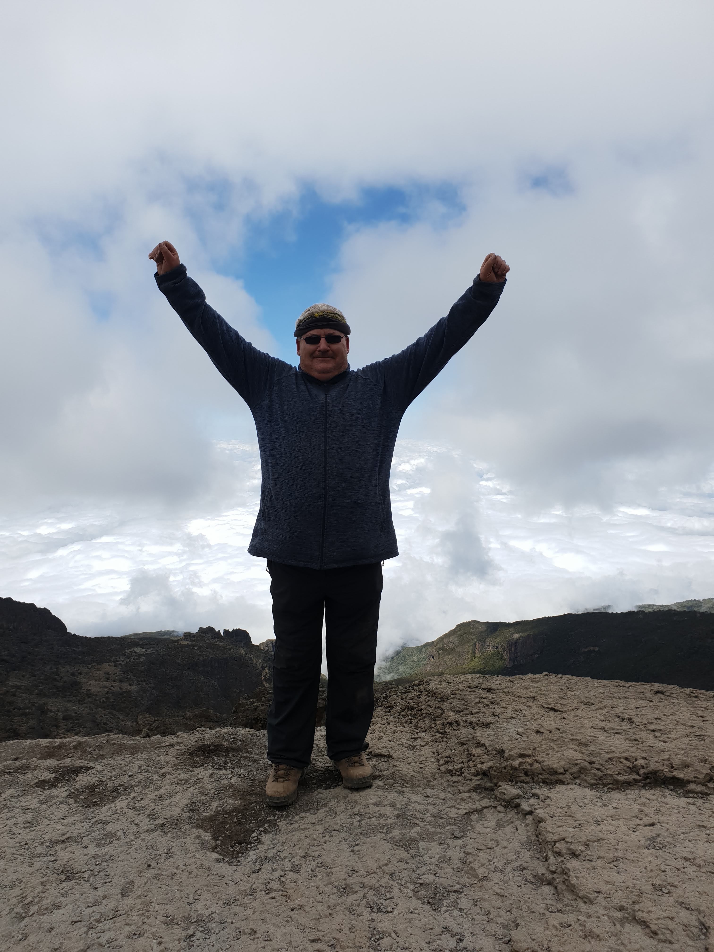 Lone climber standing above the clouds at the top of the Barranco Wall on Kilimanjaro