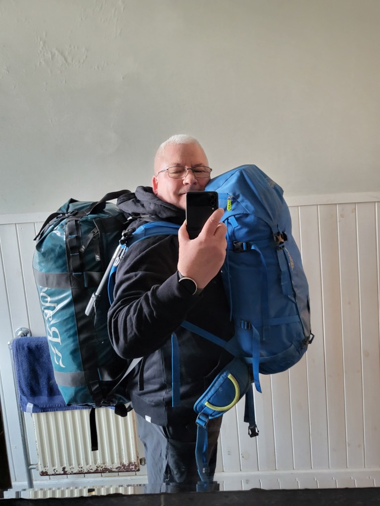 Man carrying luggage on back and front.