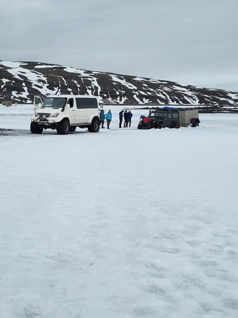 Land Rover towing minibus in deep snow.