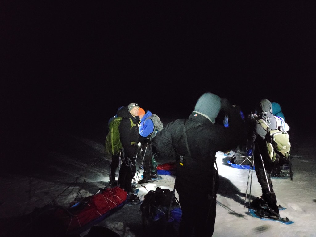 Walkers with head torches, pulkas and Snowshoes in the dark