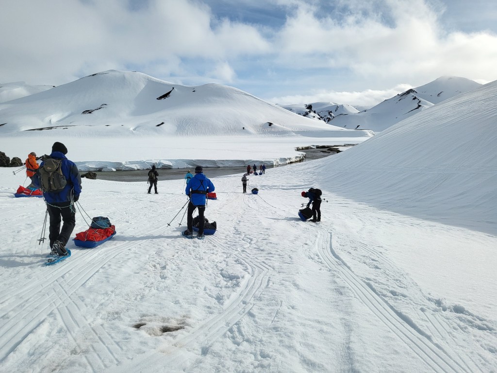 Trekkers in winter mountains with snowshoes.